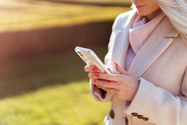 Blonde Woman in a Coat Using Her Smartphone Outdoors Free Photo