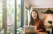 young Asian girl working at a coffee shop with a laptop