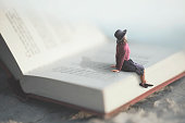 surreal moment of a woman relaxes sitting on a giant book