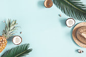 Summer composition. Tropical palm leaves, hat, fruits on blue background. Summer concept. Flat lay, top view, copy space