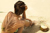 Woman with coconut drink under palm leaf