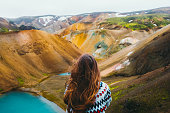 Woman traveler enjoying the view of scenic colorful rainbow mountains and turquoise lake in the wilderness