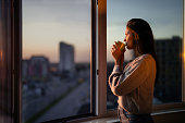 Profile view of beautiful woman drinking coffee by the window.