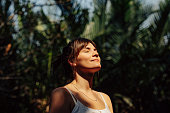 Beautiful Happy Woman Enjoying the Warm Sunlight in a Tropical Public Park