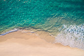 Clean ocean waves breaking on white sand beach with turquoise emerald coloured water