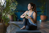 Fit woman drinking a green detox smoothie at the gym