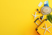 Passport, Airplane Tickets, Yellow Suitcase, Sun Hat And Protective Face Mask On Yellow Background