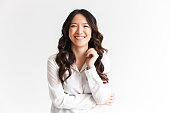 Portrait of gorgeous asian woman with long dark hair laughing at camera with beautiful smile, isolated over white background in studio