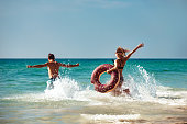 Happy young couple with inflatable donut at sea beach