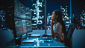 Portrait of a Financial Analyst Working on Computer with Multi-Monitor Workstation with Real-Time Stocks, Commodities and Exchange Market Charts. Businesswoman at Work in Investment Broker Agency.