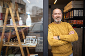 Proud owner standing with arms crossed in front of his store