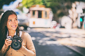 Photographer woman Asian girl taking photos with slr camera professional photography looking at San Francisco cable car tramway. Tourist taking pictures of popular attraction California, USA travel