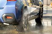 Closeup of male driver washing his car with contactless high pressure water jet in self service car wash.