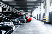 Red car paked in underground garage with lots of vehicles