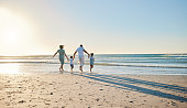 Rearview shot of a happy family walking towards the sea