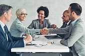 Businesswoman and businessman shaking hands across the table