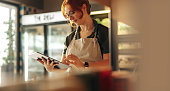 Cheerful store owner using a digital tablet in her grocery store