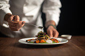 A male chef pouring sauce on meal