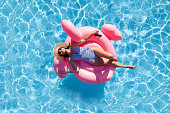 Woman relaxing on pink flamingo inflatable ring