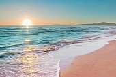 Colorful sunset viewed from the pink sea beach with soft waves