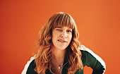 Quirky young woman winking at the camera while standing in a studio