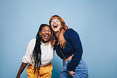 Two interracial best friends laughing and having a good time together in a studio