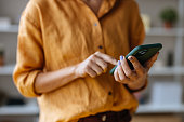 An Unrecognizable Businesswoman Using Her Mobile Phone While Working In The Office