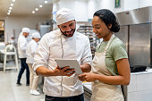 Baker training a new employee at the bakery