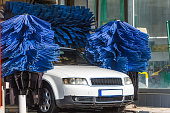 Automatic wash blue brush in action, white car comes out ready clean.