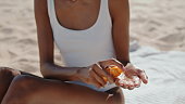 Hands spray sun protection oil closeup. Attractive girl sunbathing at seashore