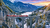 Aerial view of Train passing through famous mountain in Filisur, Switzerland. Landwasser Viaduct world heritage with train express in Swiss Alps snow winter scenery.