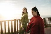 Two women walking by the sea at sunset