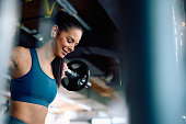 Young sportswoman having weight training with barbell in a gym.