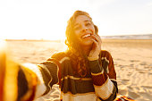 Young woman posing by the sea at sunset.