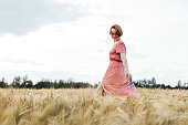 Young adult woman walking through the meadow field