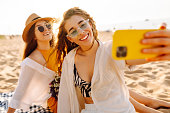 Selfie time. Two young women posing by the sea at sunset.