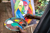 African painter using brush and palette to paint a picture