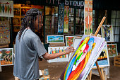 Young african artist painting a colorful animal on canvas