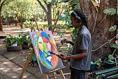 African painter listening to music painting a picture outdoors