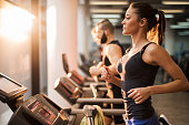 People running on a treadmill in health club.