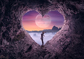 Single woman in heart shape cave towards the idyllic scenery