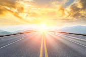 asphalt road and mountains with foggy landscape at sunset