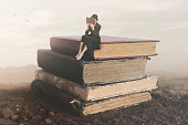 Surreal image of a woman reading sitting on top of a book