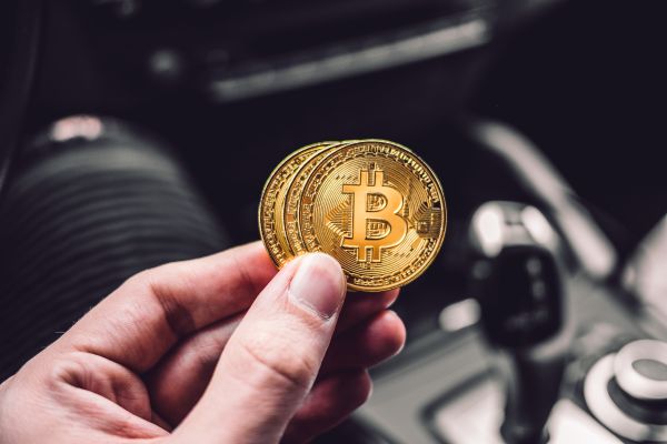 Man Holding a Bitcoin Coin in a Car Free Photo