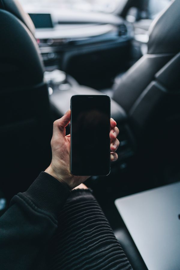 Man Sitting in a Car and Holding an iPhone Free Photo