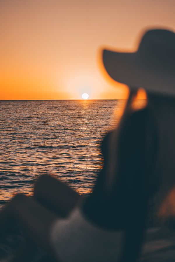 Woman in a Hat Looking at Sunset Above The Sea Free Photo