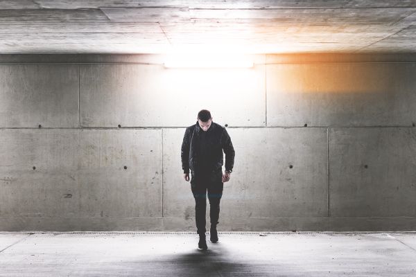 Young Man Walking in Conrete Underground Walkway Free Photo